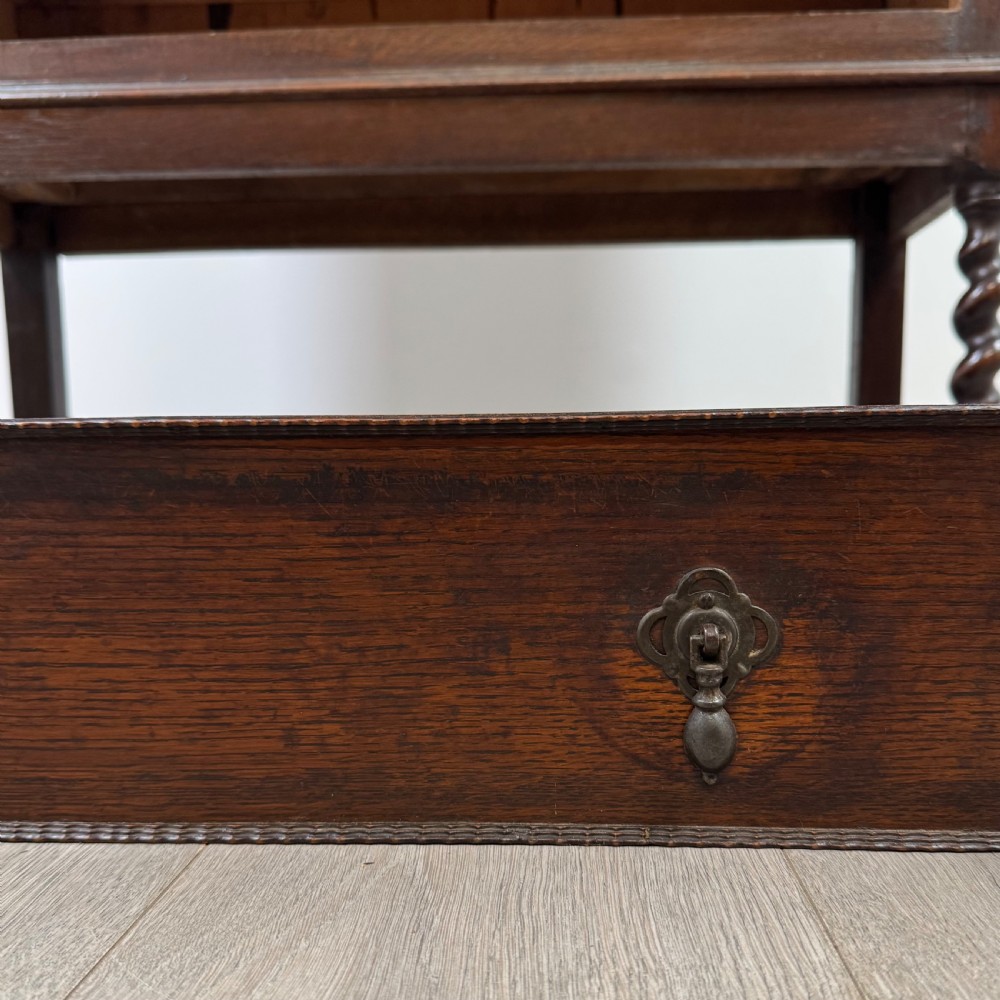 A dark oak Edwardian glazed display cabinet featuring two leaded glass doors, a lower drawer, and barley twist legs connected by stretchers. View XIII
