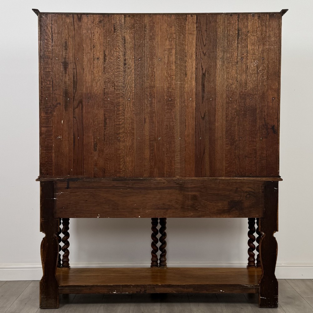 A golden oak kitchen dresser featuring an upper shelving rack with side cupboards and a lower base with two drawers, barley twist legs, and an open pot board. View VI