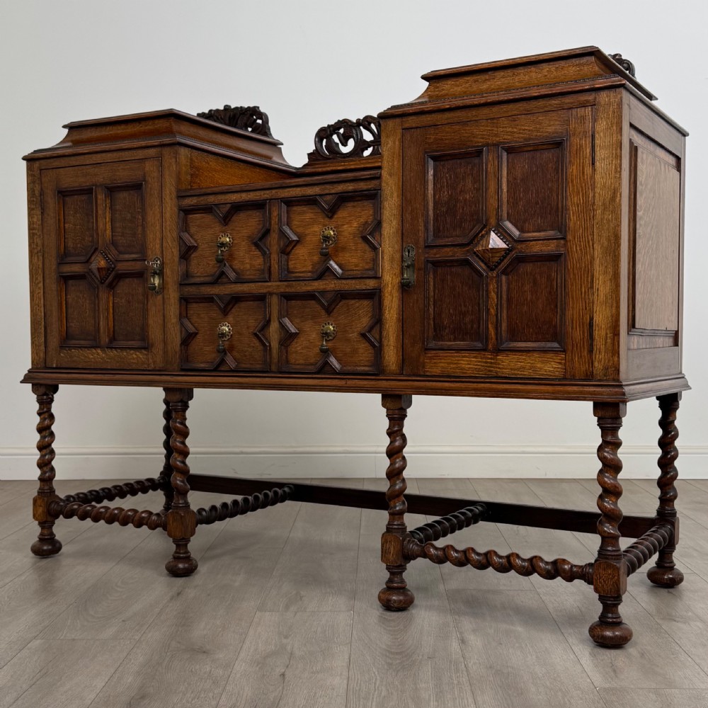 A 20th-century Jacobean style golden oak sideboard featuring geometric moulding, central drawers, cupboard doors, and barley twist legs. View III