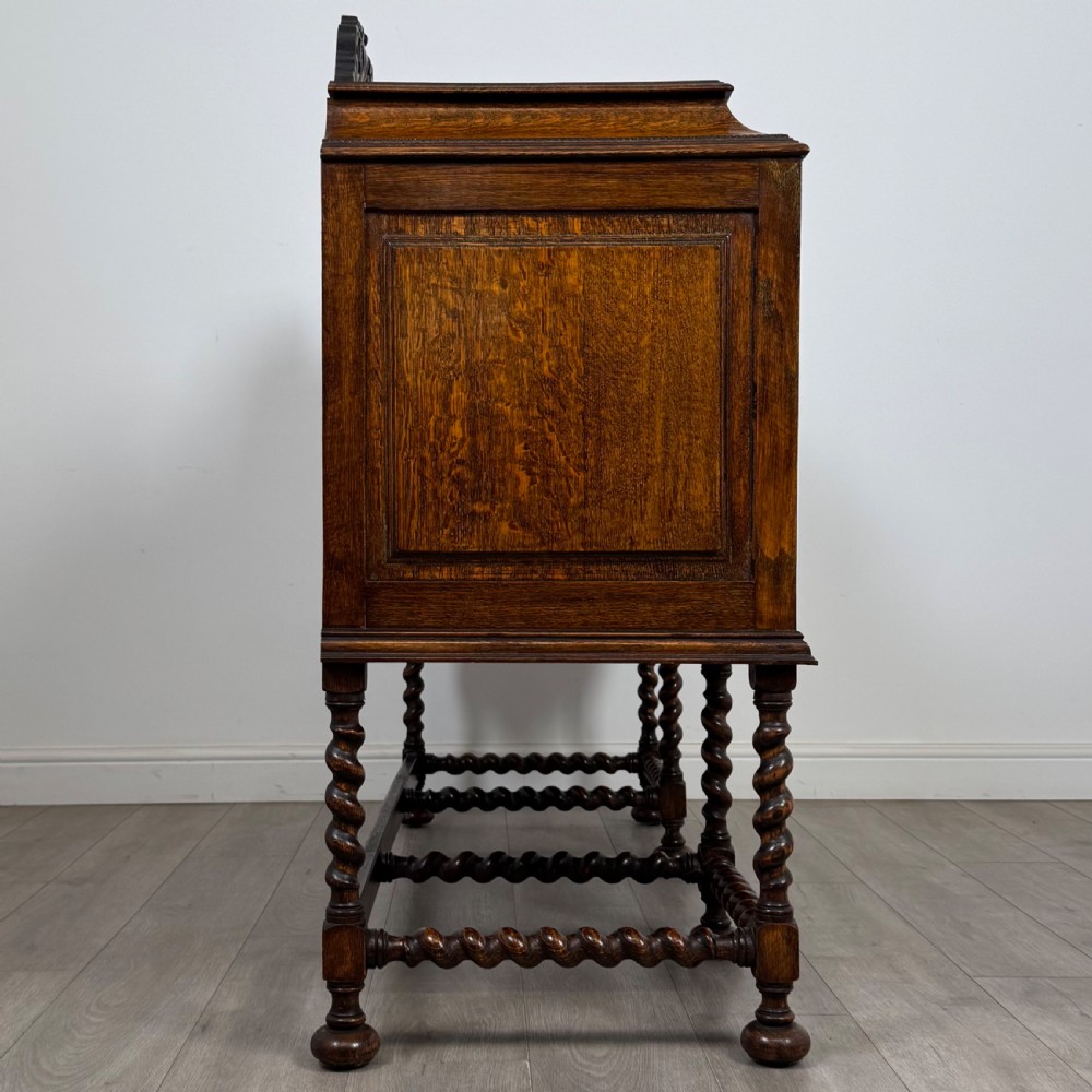 A 20th-century Jacobean style golden oak sideboard featuring geometric moulding, central drawers, cupboard doors, and barley twist legs. View VIII