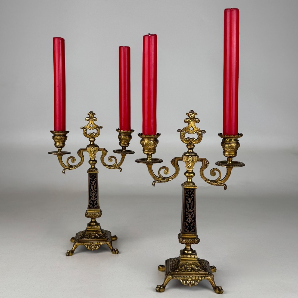 A pair of 19th-century French brass candelabra featuring ornate scrollwork arms and dark enamel inlaid details. View II
