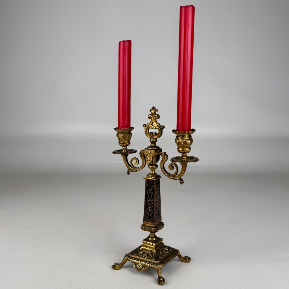 A pair of 19th-century French brass candelabra featuring ornate scrollwork arms and dark enamel inlaid details. View IV