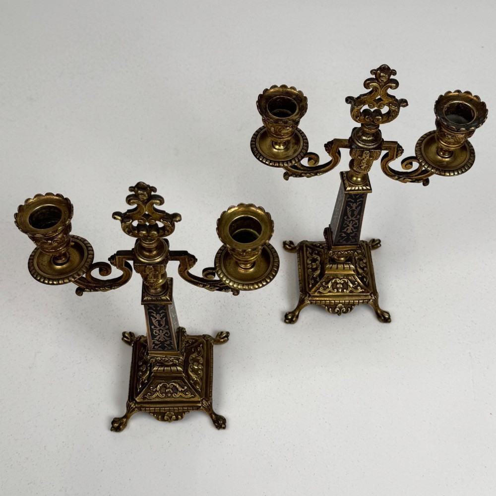 A pair of 19th-century French brass candelabra featuring ornate scrollwork arms and dark enamel inlaid details. View VIII