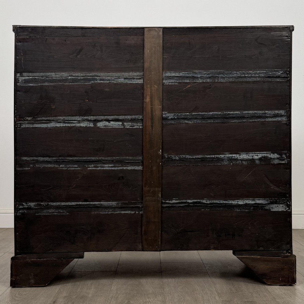 An 18th-century Georgian oak chest of drawers featuring two short drawers over three long drawers, brass handles, crossbanded inlay, reeded side columns, and bracket feet. View V