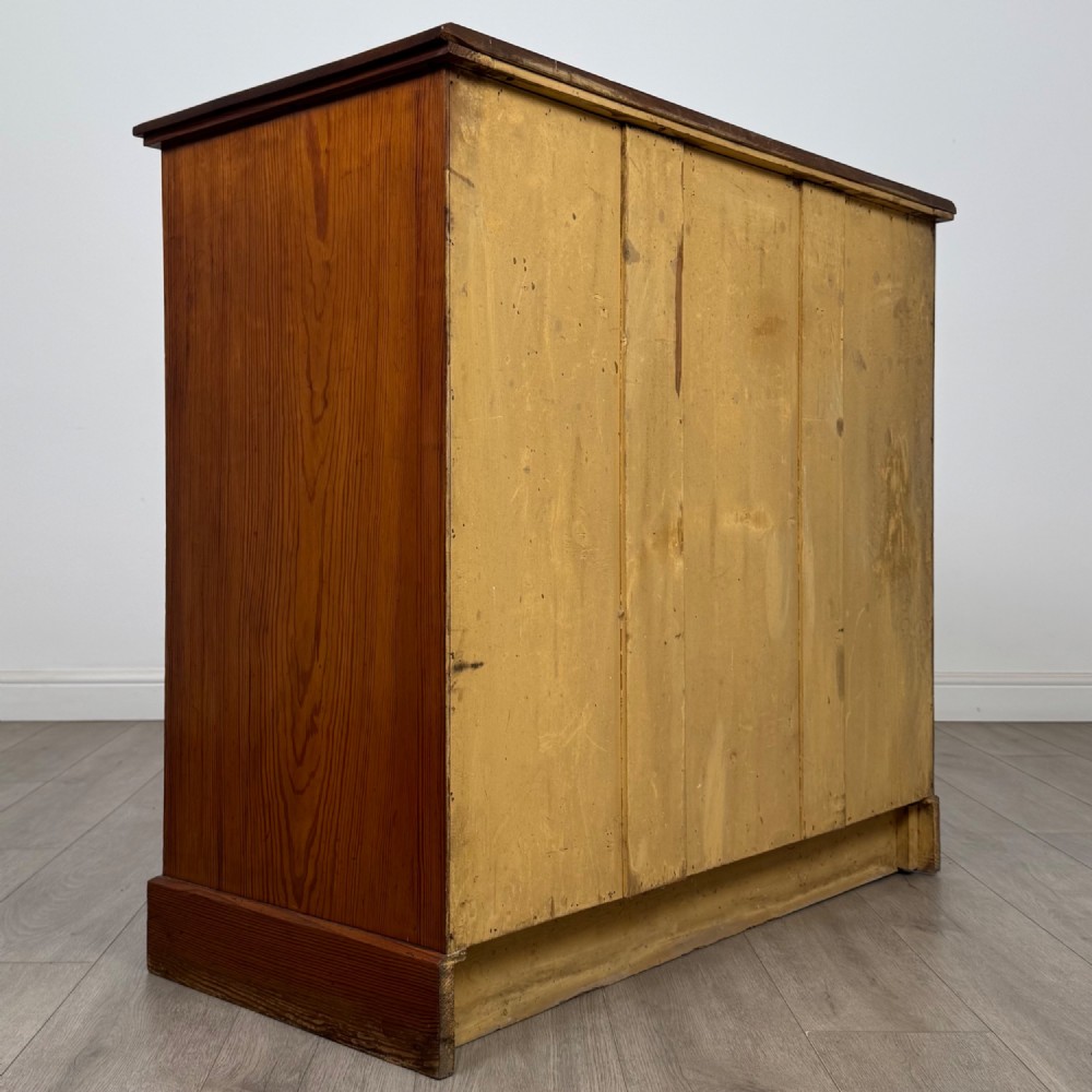 A Victorian nineteenth-century pitch pine chest of drawers featuring a prominent figured wood grain, brass drop handles, a two-over-three drawer configuration, and a shaped apron base. View IV