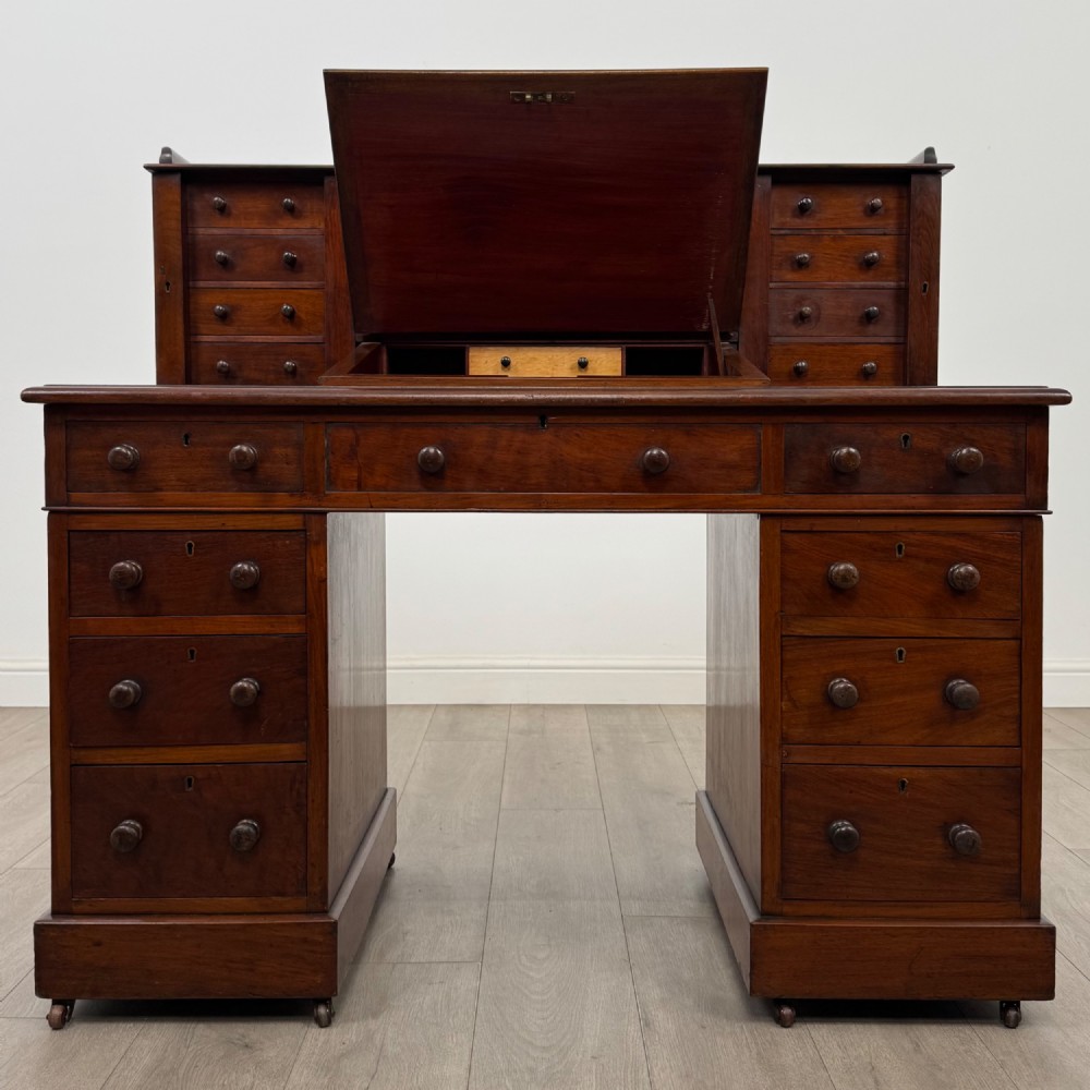 A 19th-century Victorian mahogany Dickens desk featuring a twin-pedestal design, raised superstructure with drawers and spindle gallery, slant writing surface, turned timber knobs, and plinth bases. View II