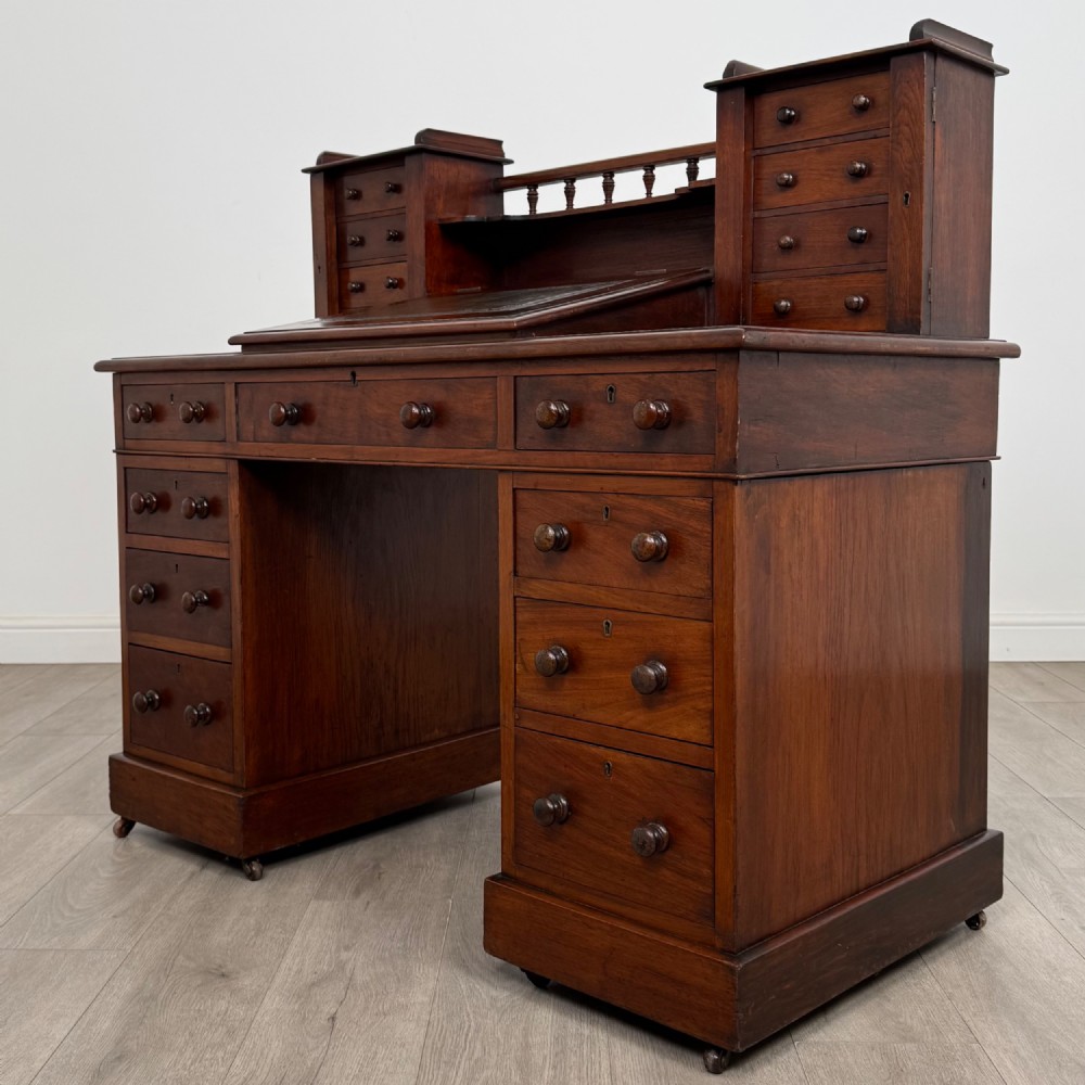 A 19th-century Victorian mahogany Dickens desk featuring a twin-pedestal design, raised superstructure with drawers and spindle gallery, slant writing surface, turned timber knobs, and plinth bases. View III
