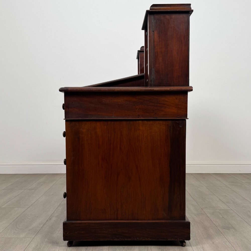 A 19th-century Victorian mahogany Dickens desk featuring a twin-pedestal design, raised superstructure with drawers and spindle gallery, slant writing surface, turned timber knobs, and plinth bases. View IV
