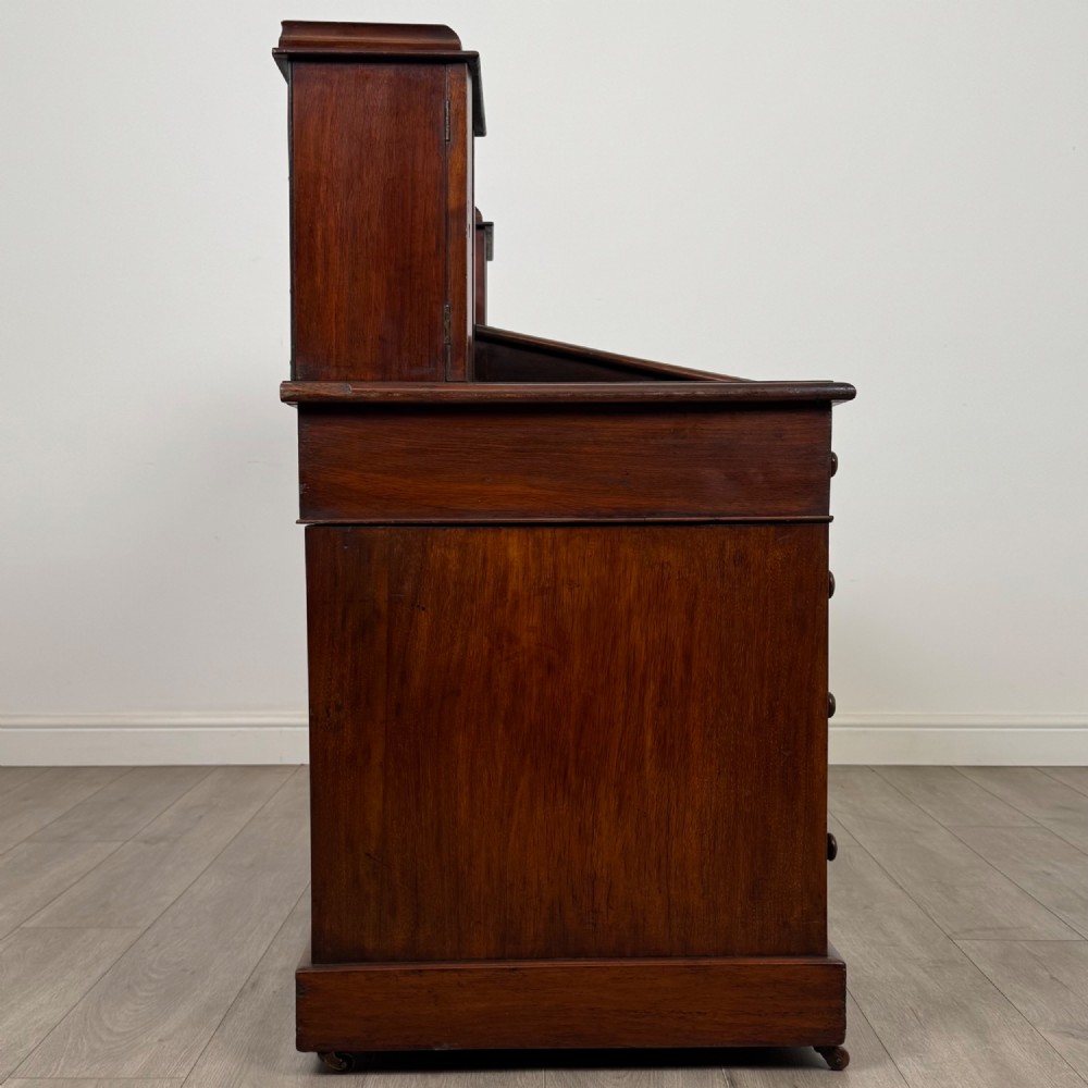 A 19th-century Victorian mahogany Dickens desk featuring a twin-pedestal design, raised superstructure with drawers and spindle gallery, slant writing surface, turned timber knobs, and plinth bases. View VIII