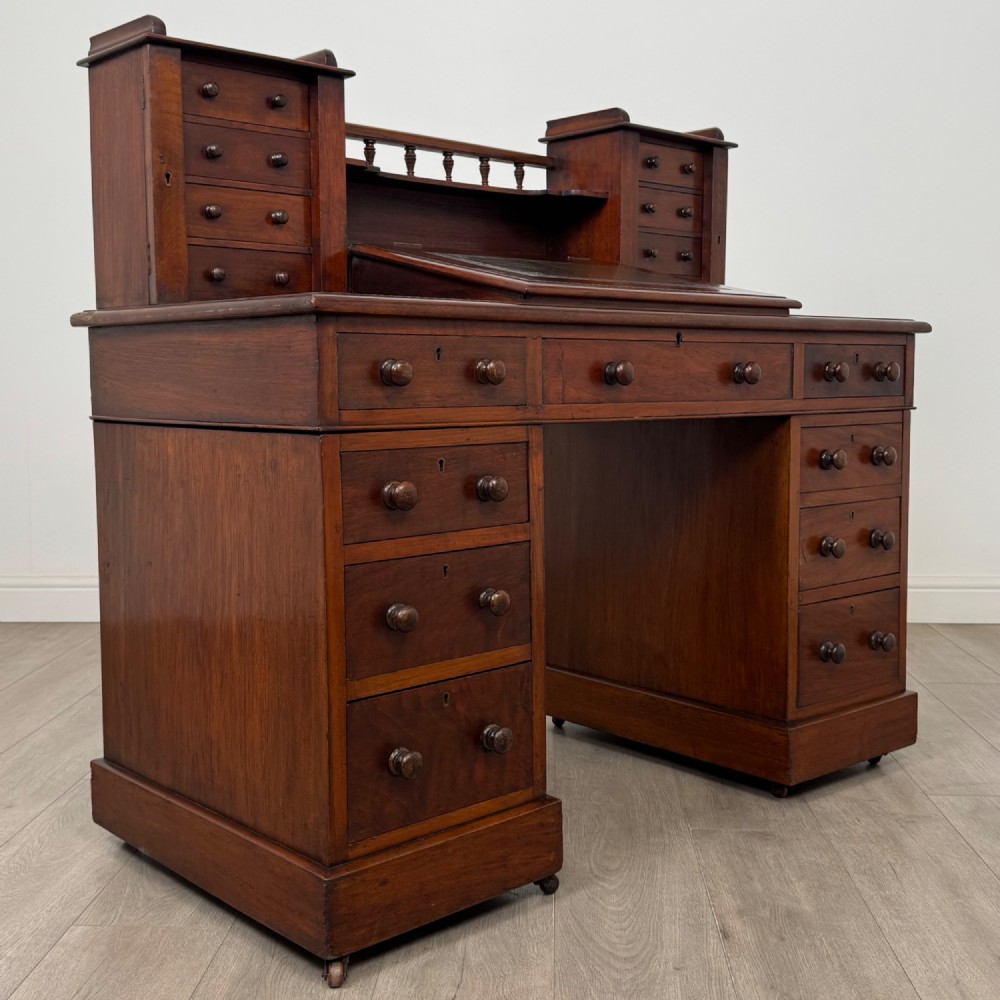 A 19th-century Victorian mahogany Dickens desk featuring a twin-pedestal design, raised superstructure with drawers and spindle gallery, slant writing surface, turned timber knobs, and plinth bases. View IX
