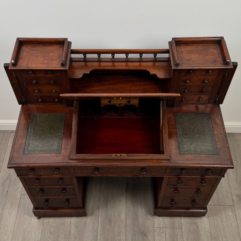 A 19th-century Victorian mahogany Dickens desk featuring a twin-pedestal design, raised superstructure with drawers and spindle gallery, slant writing surface, turned timber knobs, and plinth bases. View XI