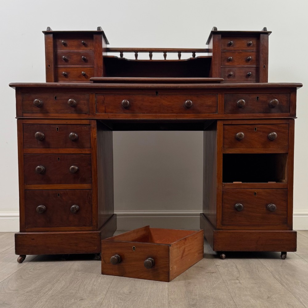 A 19th-century Victorian mahogany Dickens desk featuring a twin-pedestal design, raised superstructure with drawers and spindle gallery, slant writing surface, turned timber knobs, and plinth bases. View XII