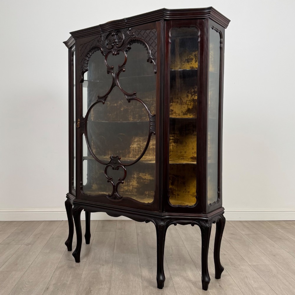 A dark mahogany display cabinet featuring glazed panels, detailed carved fretwork on the central door, and cabriole legs. View III