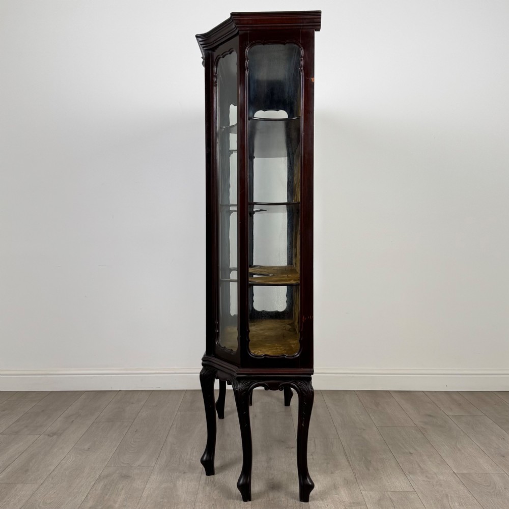 A dark mahogany display cabinet featuring glazed panels, detailed carved fretwork on the central door, and cabriole legs. View IV