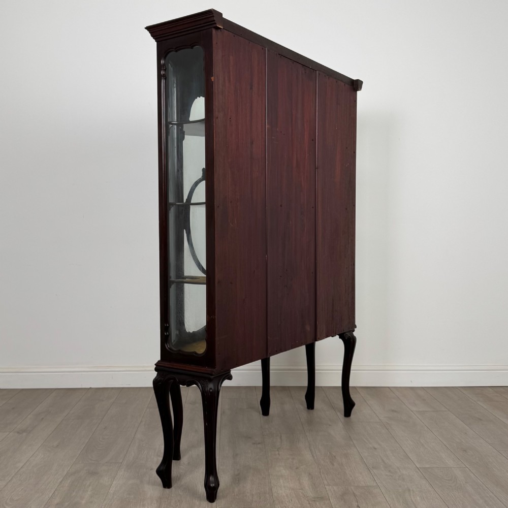 A dark mahogany display cabinet featuring glazed panels, detailed carved fretwork on the central door, and cabriole legs. View V