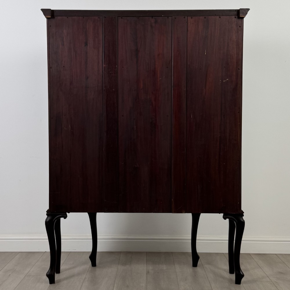 A dark mahogany display cabinet featuring glazed panels, detailed carved fretwork on the central door, and cabriole legs. View VI