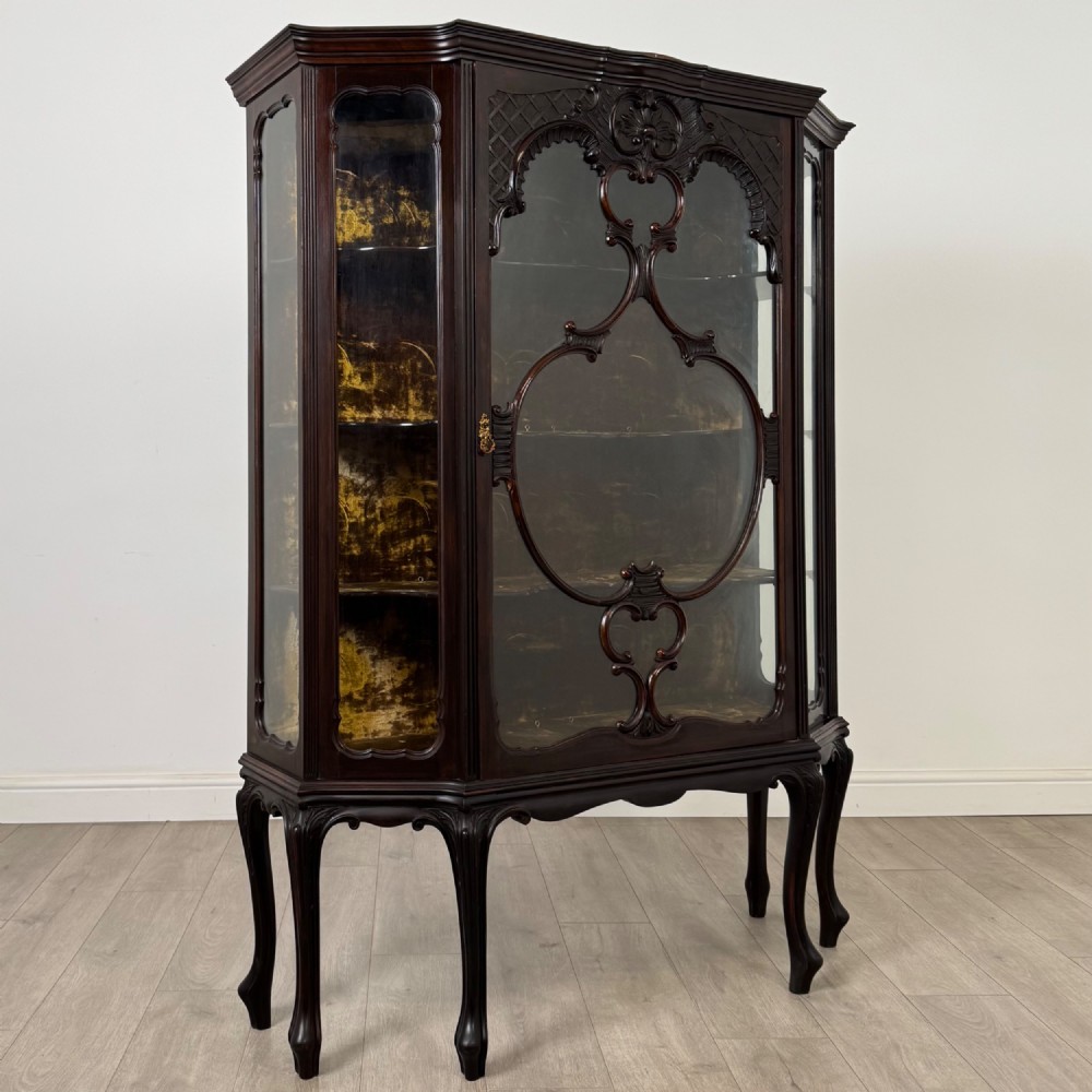 A dark mahogany display cabinet featuring glazed panels, detailed carved fretwork on the central door, and cabriole legs. View IX