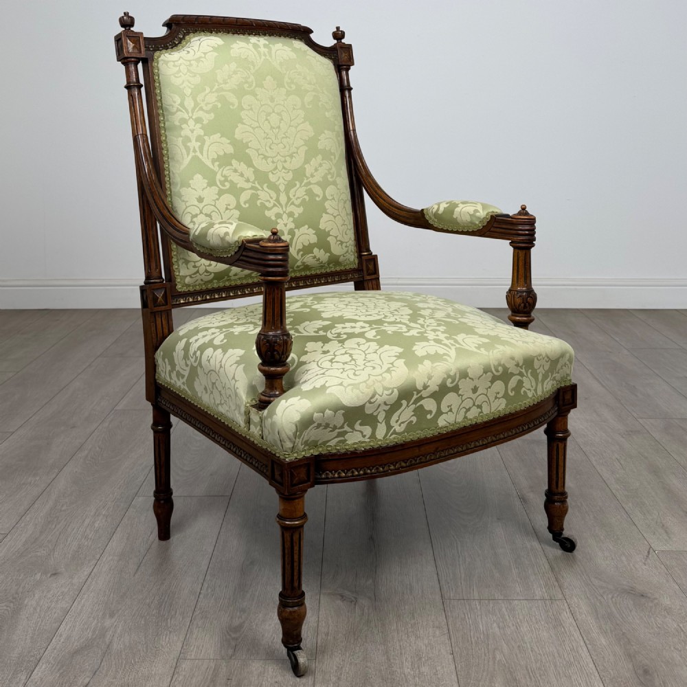 A 19th-century French open armchair featuring a carved walnut frame, fluted legs on brass castors, and green floral damask upholstery. View VII