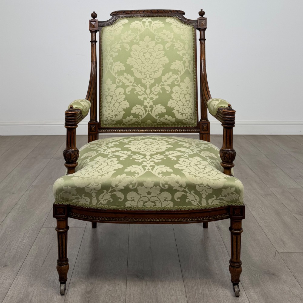 A 19th-century French open armchair featuring a carved walnut frame, fluted legs on brass castors, and green floral damask upholstery. View VIII