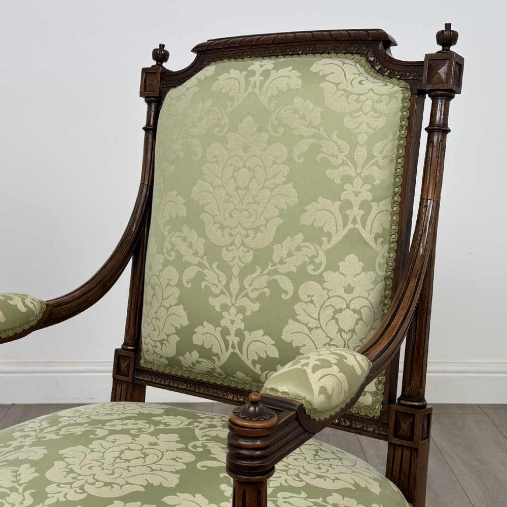A 19th-century French open armchair featuring a carved walnut frame, fluted legs on brass castors, and green floral damask upholstery. View IX