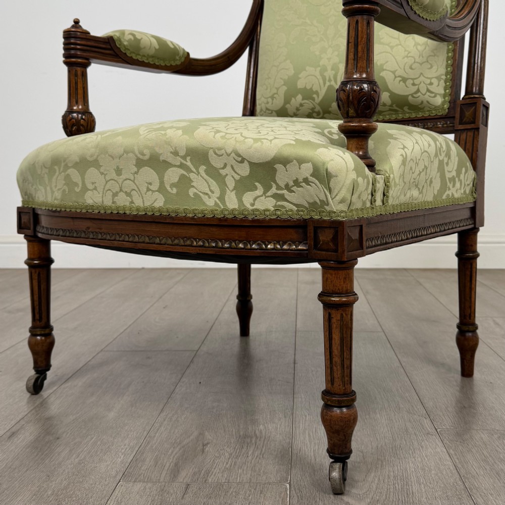 A 19th-century French open armchair featuring a carved walnut frame, fluted legs on brass castors, and green floral damask upholstery. View XI