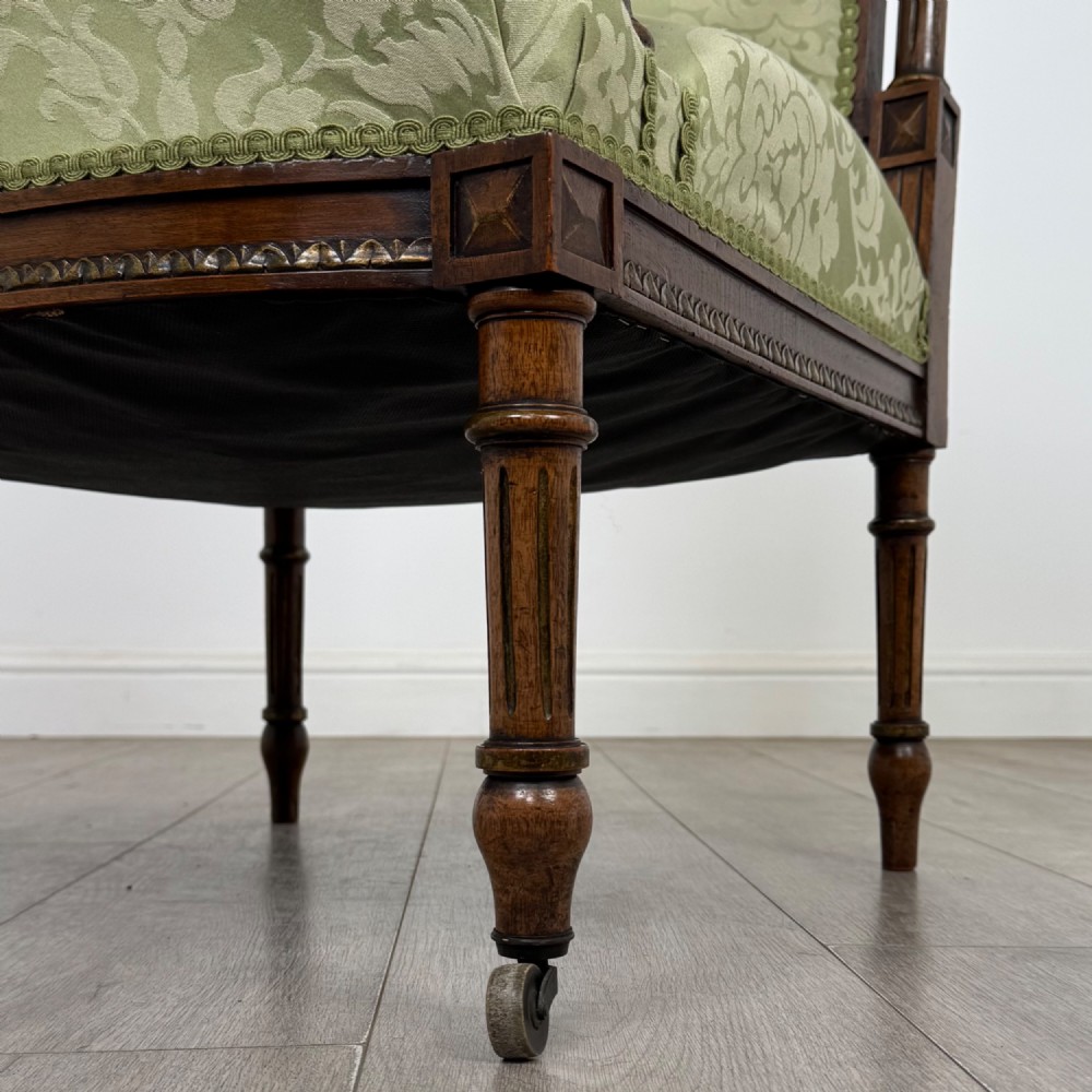 A 19th-century French open armchair featuring a carved walnut frame, fluted legs on brass castors, and green floral damask upholstery. View XII