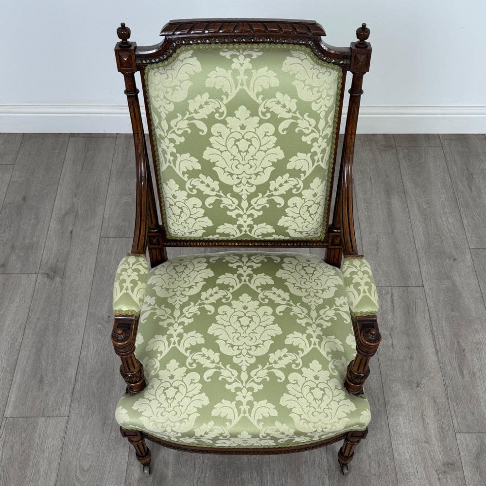A 19th-century French open armchair featuring a carved walnut frame, fluted legs on brass castors, and green floral damask upholstery. View XIII