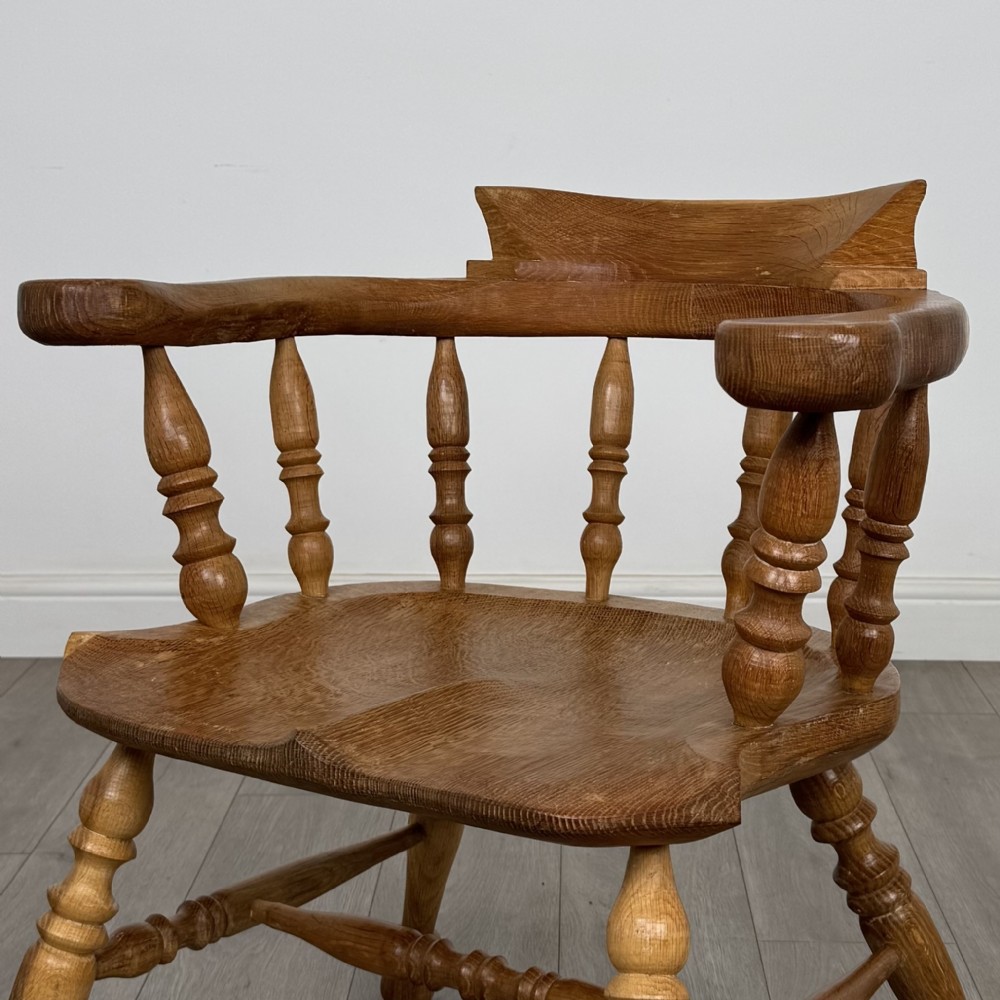 A solid oak smokers bow armchair featuring a shaped saddle seat, turned spindles, curved handrests, and splayed legs. View IX
