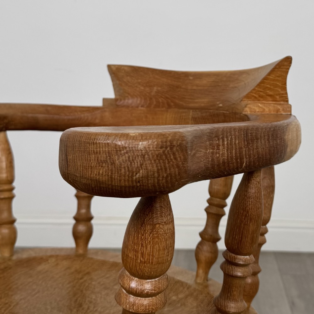 A solid oak smokers bow armchair featuring a shaped saddle seat, turned spindles, curved handrests, and splayed legs. View X