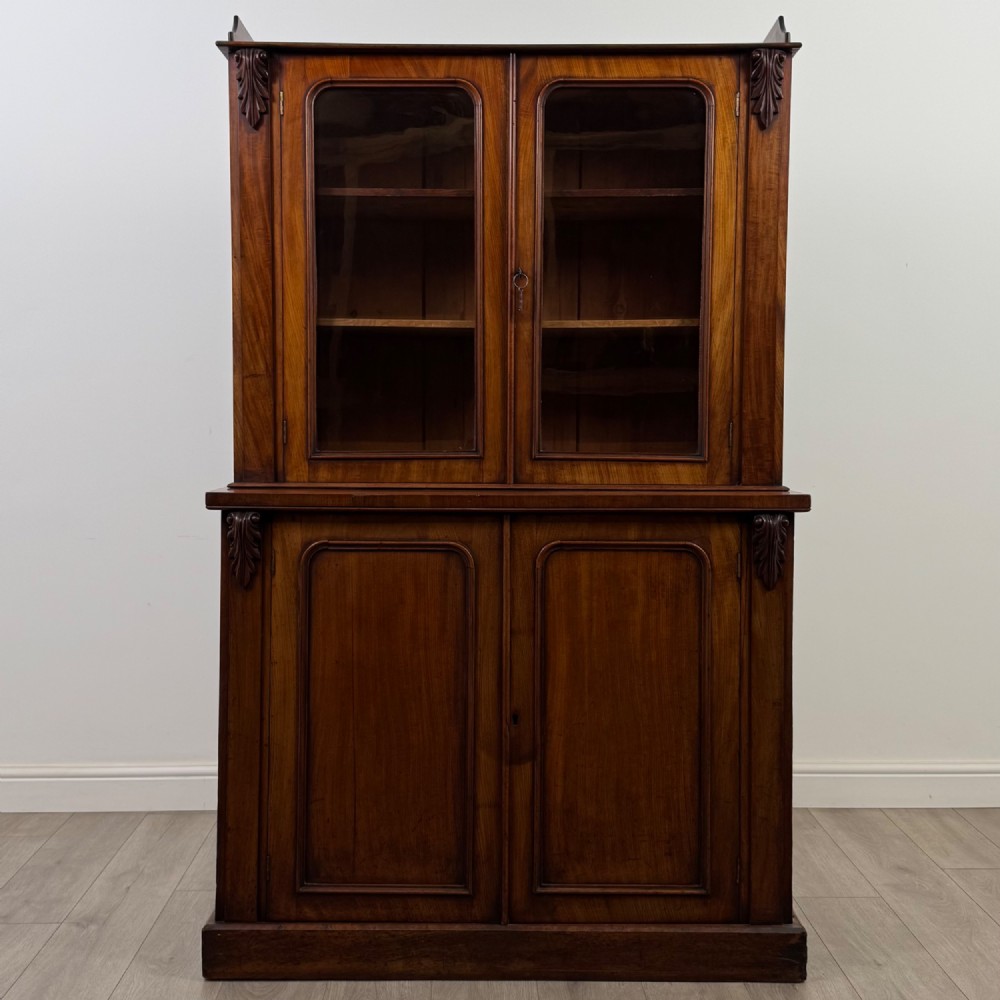 A 19th-century Victorian mahogany bookcase featuring a glazed upper display cabinet with carved corbels above a two-door solid cupboard base. View II