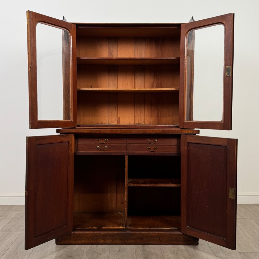 A 19th-century Victorian mahogany bookcase featuring a glazed upper display cabinet with carved corbels above a two-door solid cupboard base. View III
