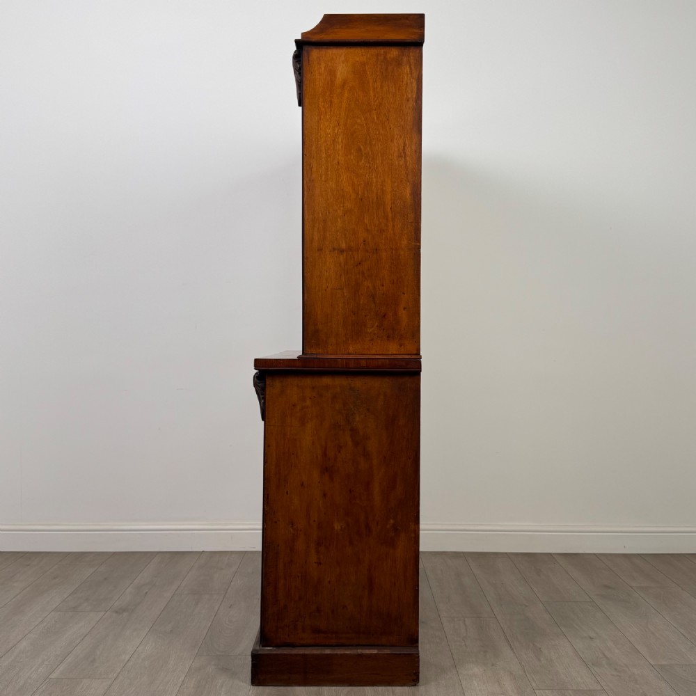 A 19th-century Victorian mahogany bookcase featuring a glazed upper display cabinet with carved corbels above a two-door solid cupboard base. View V