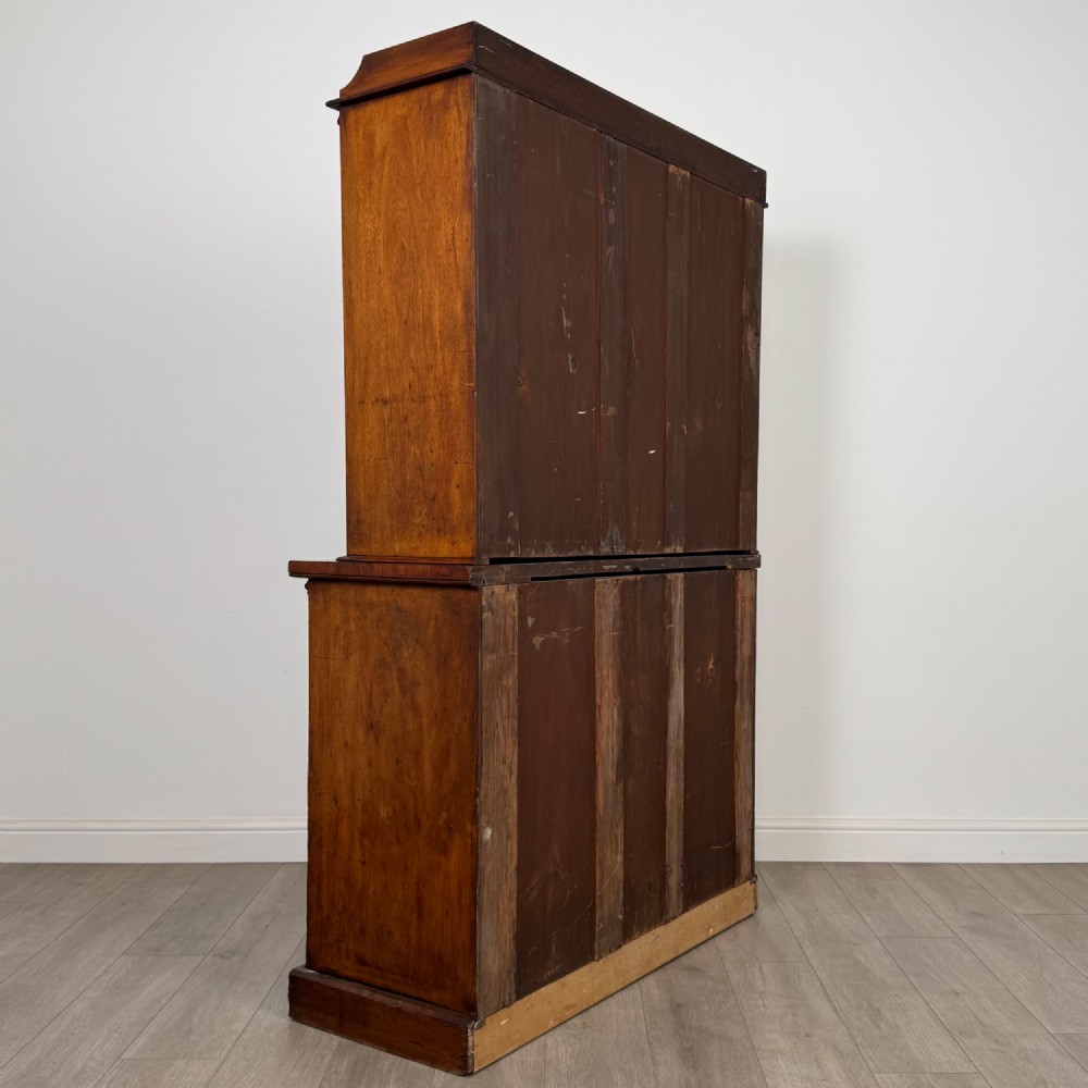 A 19th-century Victorian mahogany bookcase featuring a glazed upper display cabinet with carved corbels above a two-door solid cupboard base. View VI