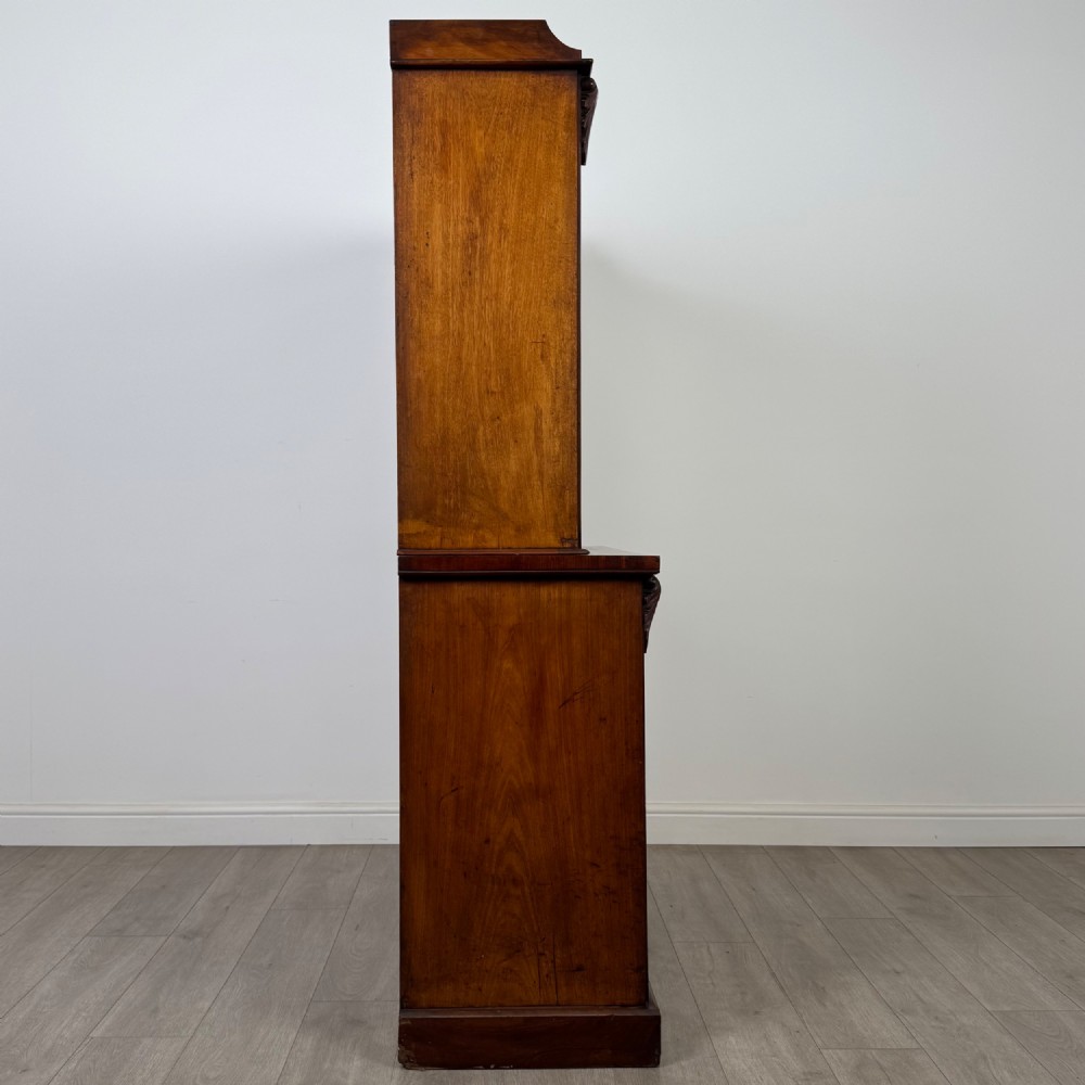 A 19th-century Victorian mahogany bookcase featuring a glazed upper display cabinet with carved corbels above a two-door solid cupboard base. View IX