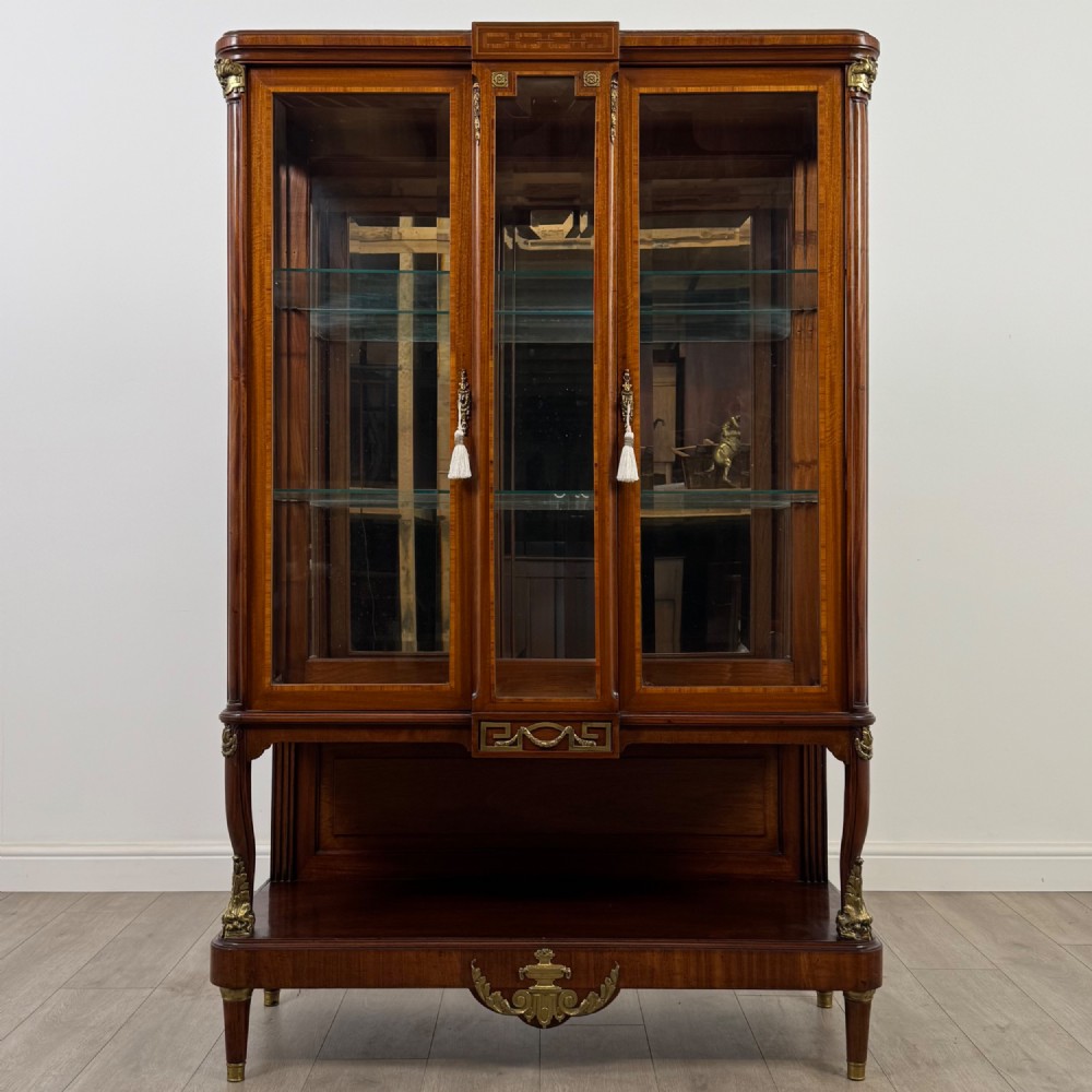 A nineteenth-century French mahogany glazed display cabinet featuring gilt-bronze mounts, glass shelving, and an open lower tier.