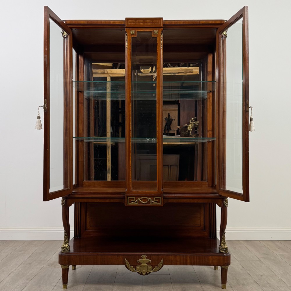 A nineteenth-century French mahogany glazed display cabinet featuring gilt-bronze mounts, glass shelving, and an open lower tier. View II