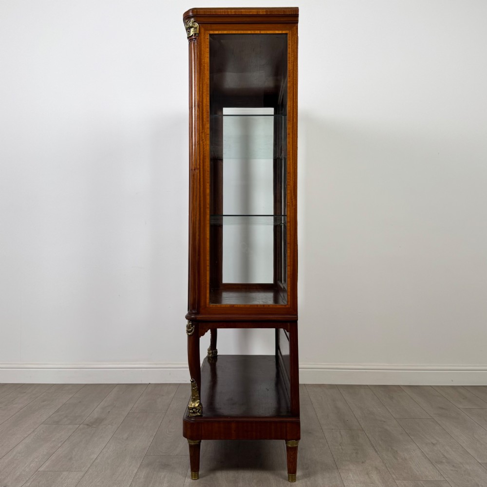 A nineteenth-century French mahogany glazed display cabinet featuring gilt-bronze mounts, glass shelving, and an open lower tier. View IV