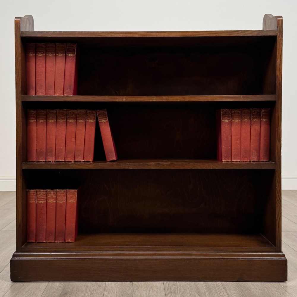 A twentieth-century dark oak open bookcase with three fitted shelves and profiled side edges.
