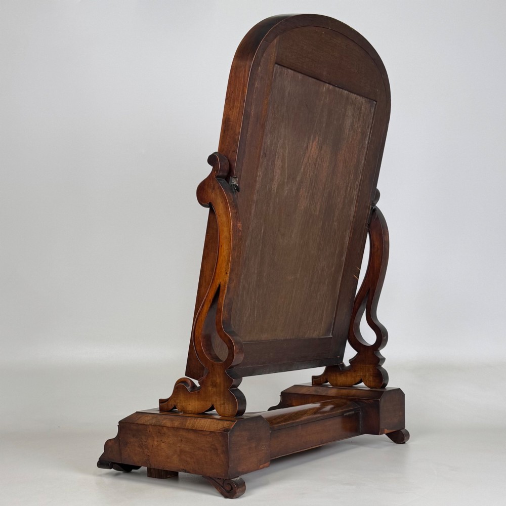 An antique Victorian dark mahogany tabletop dressing mirror featuring an arched frame supported by carved scroll uprights on a plinth base. View VI