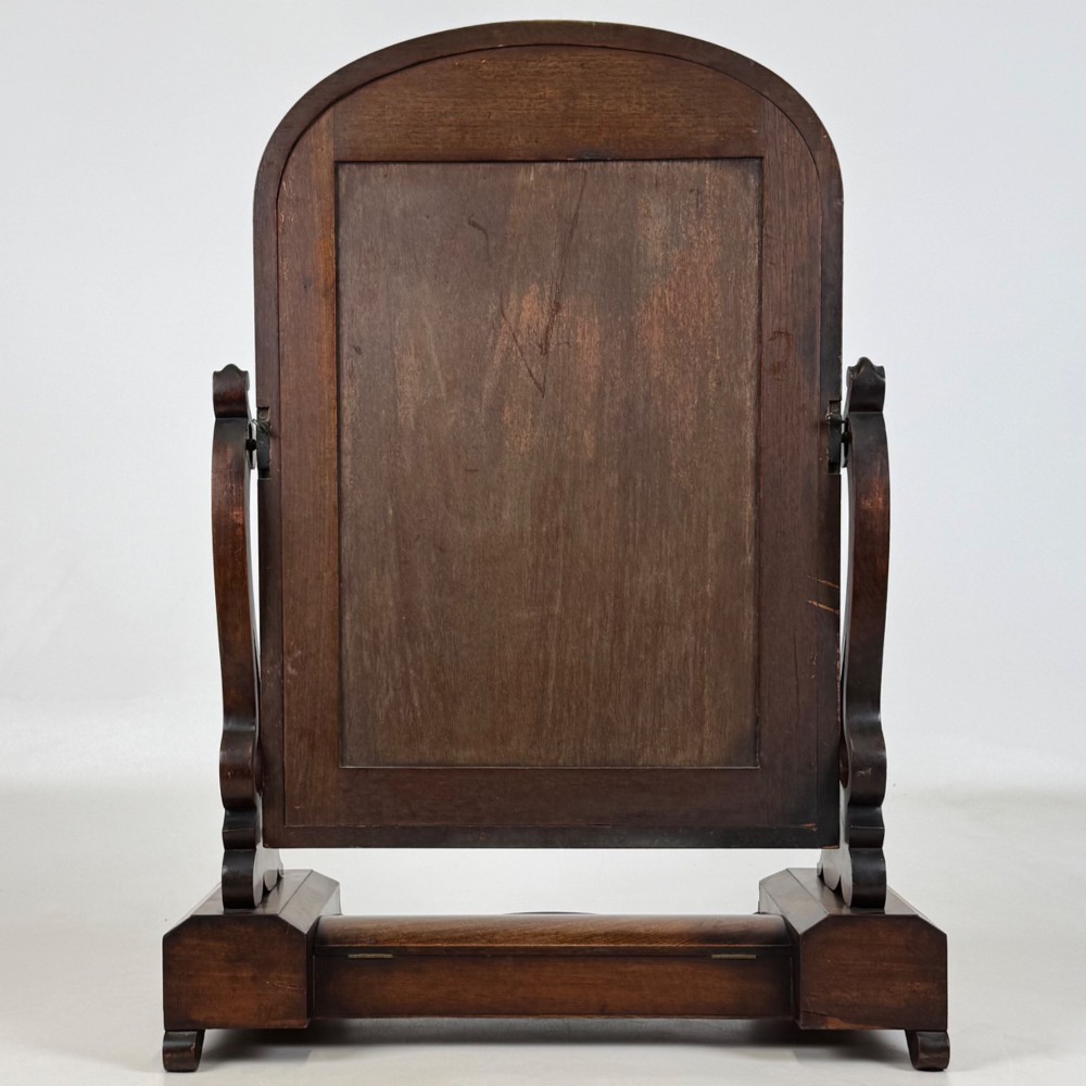 An antique Victorian dark mahogany tabletop dressing mirror featuring an arched frame supported by carved scroll uprights on a plinth base. View VII