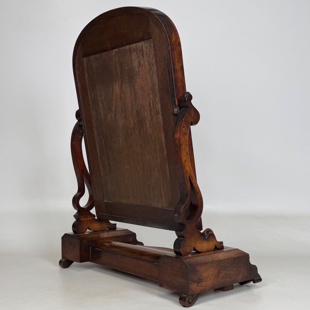 An antique Victorian dark mahogany tabletop dressing mirror featuring an arched frame supported by carved scroll uprights on a plinth base. View VIII