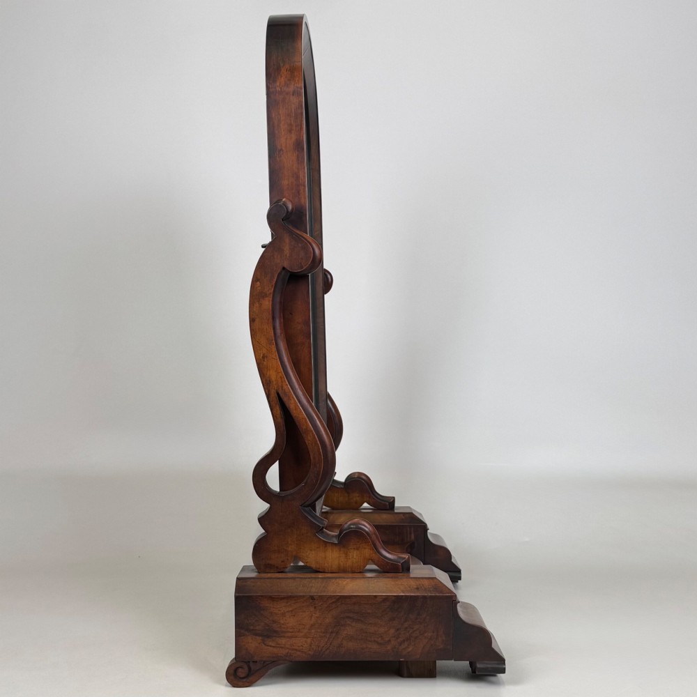 An antique Victorian dark mahogany tabletop dressing mirror featuring an arched frame supported by carved scroll uprights on a plinth base. View IX