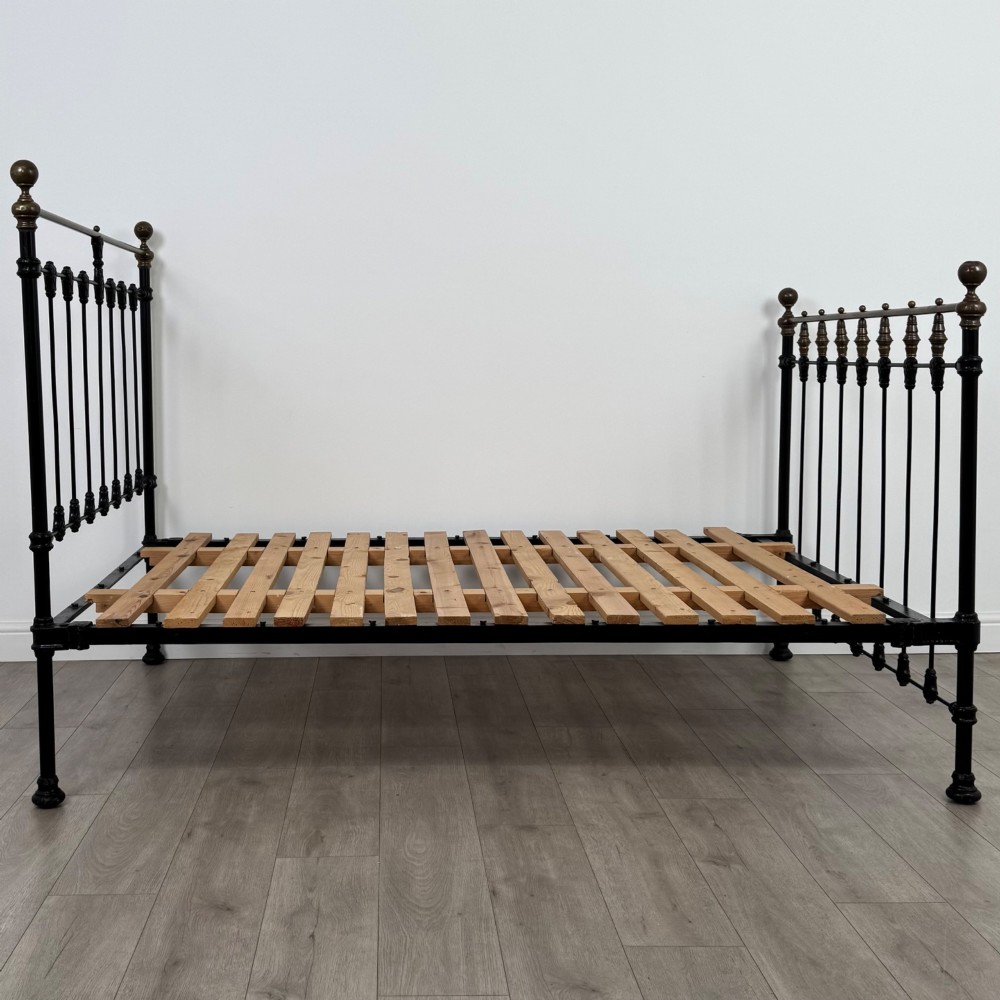 A 19th-century double bedstead featuring a black iron spindle frame with polished brass top rails and finials. View III