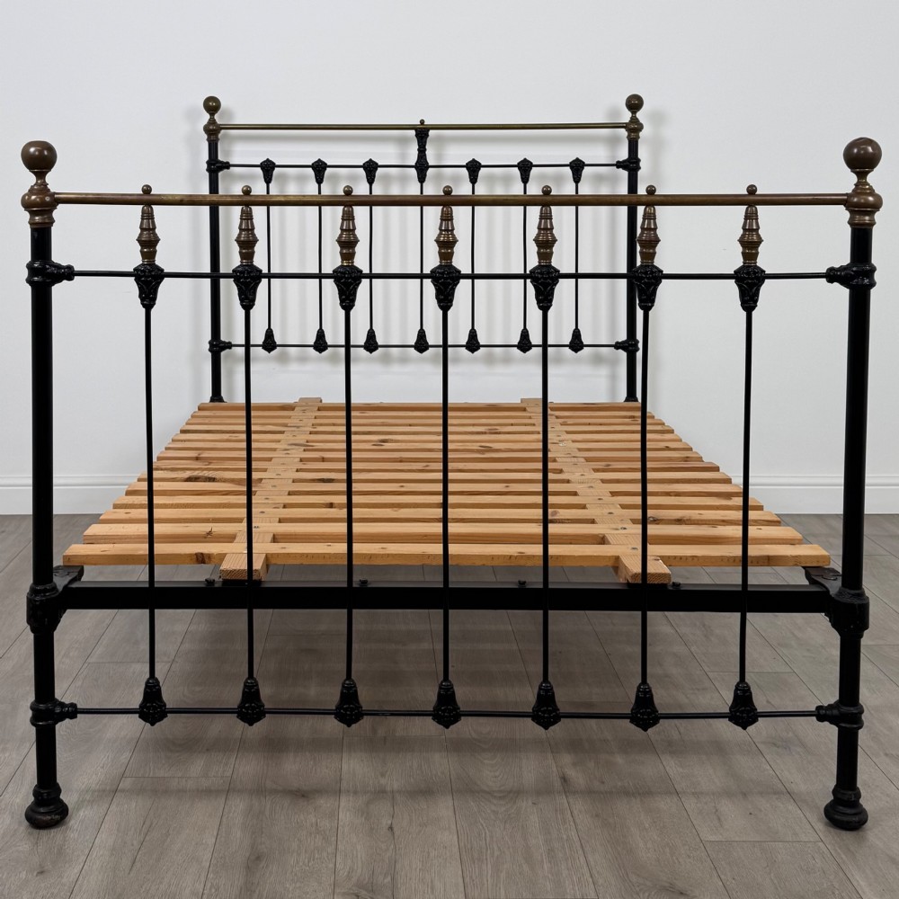 A 19th-century double bedstead featuring a black iron spindle frame with polished brass top rails and finials. View IV