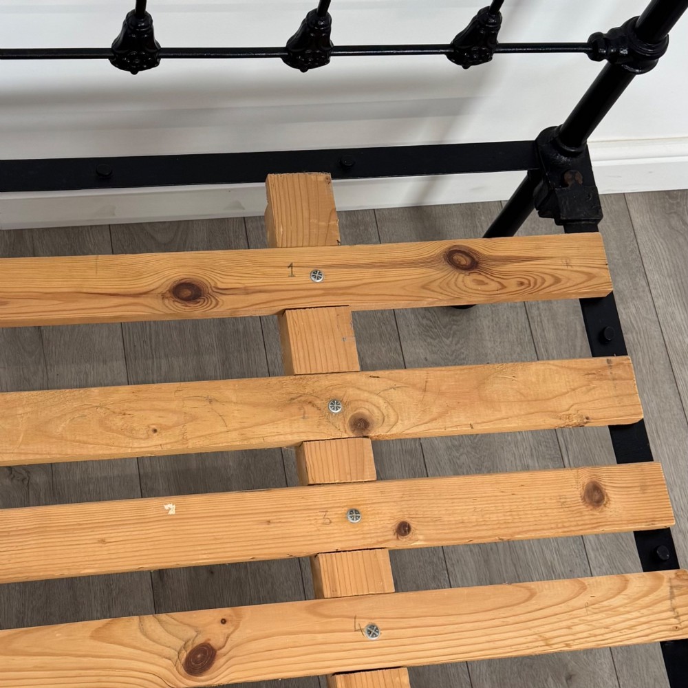 A 19th-century double bedstead featuring a black iron spindle frame with polished brass top rails and finials. View VII