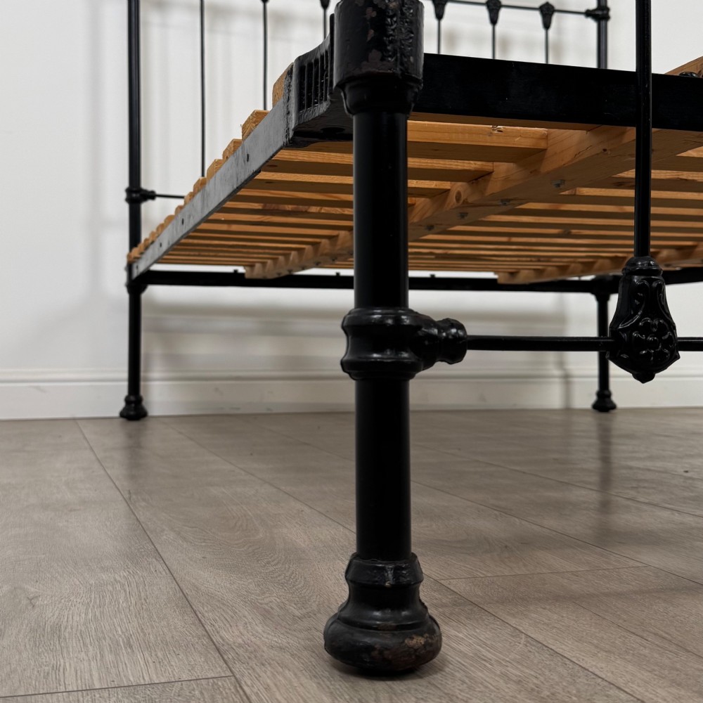 A 19th-century double bedstead featuring a black iron spindle frame with polished brass top rails and finials. View VIII