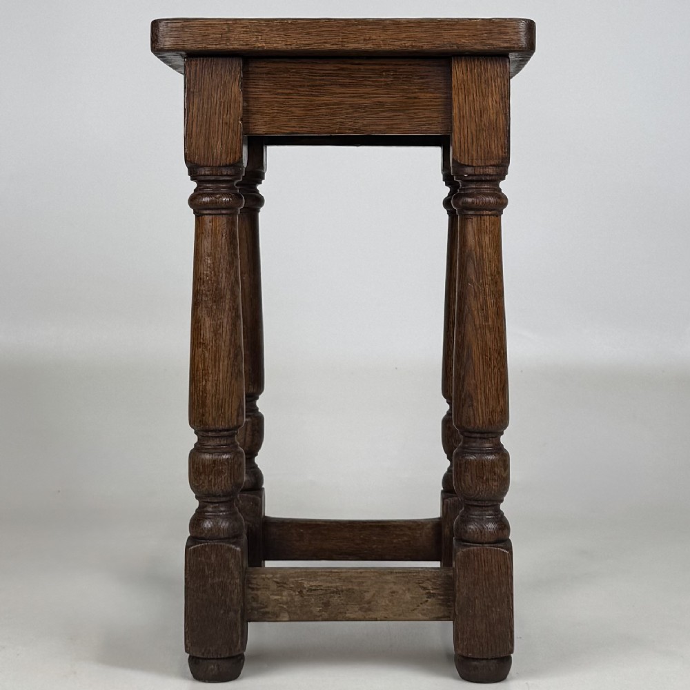 A set of three dark oak Edwardian stools featuring rectangular wooden tops, turned legs, and lower perimeter stretchers. View II