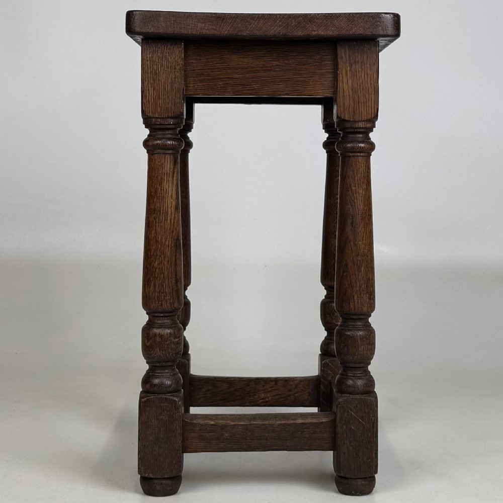 A set of three dark oak Edwardian stools featuring rectangular wooden tops, turned legs, and lower perimeter stretchers. View IV