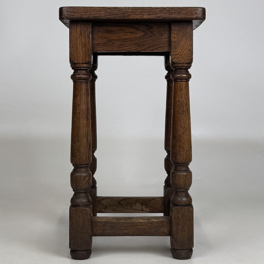 A set of three dark oak Edwardian stools featuring rectangular wooden tops, turned legs, and lower perimeter stretchers. View VI