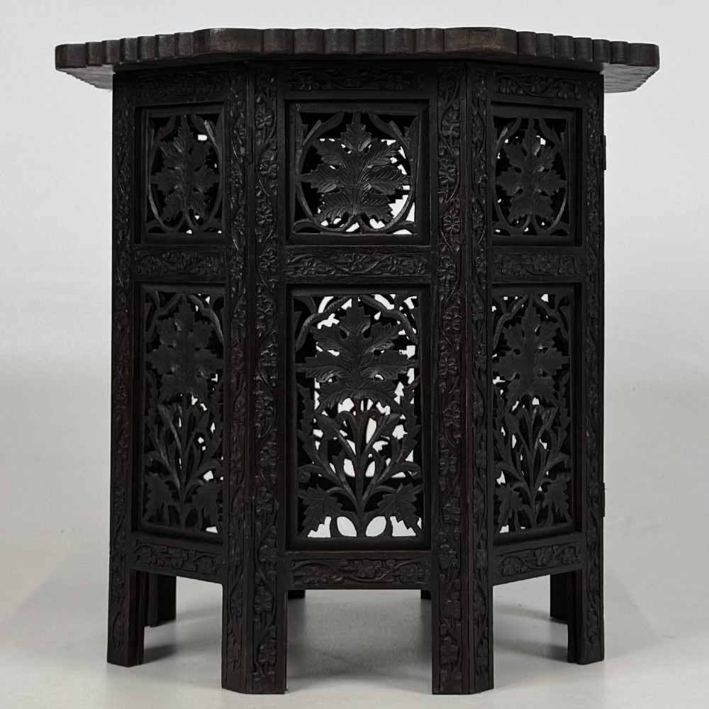 A dark brown octagonal wooden side table featuring intricate hand-carved foliate openwork panels across every side.